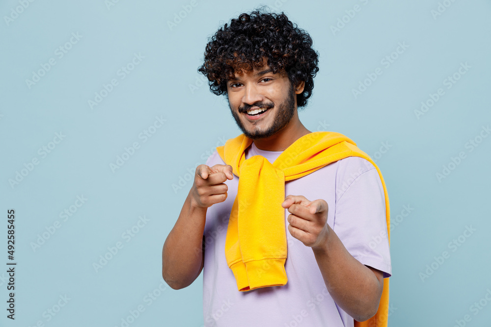 Overjoyed exultant young bearded Indian man 20s years old wears white t-shirt pointing index fingers camera on you motivating encourage isolated on plain pastel light blue background studio portrait. Overjoyed exultant young bearded Indian man 20s years old wears white t-shirt pointing index fingers camera on you motivating encourage isolated on plain pastel light blue background studio portrait.