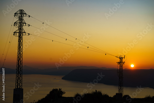 High voltage towers on coast at sunset