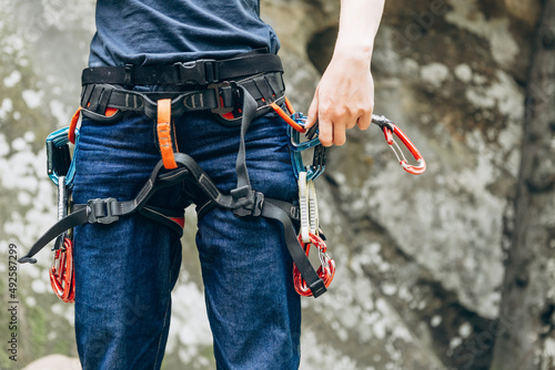 Climbing equipment, carabiners, harness, belay, close-up of a rock-climber put on by a girl, the traveler leads an active lifestyle and is engaged in mountaineering
