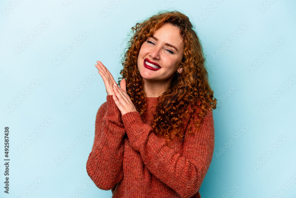 Young ginger caucasian woman isolated on blue background feeling energetic and comfortable, rubbing hands confident. Young ginger caucasian woman isolated on blue background feeling energetic and comfortable, rubbing hands confident.