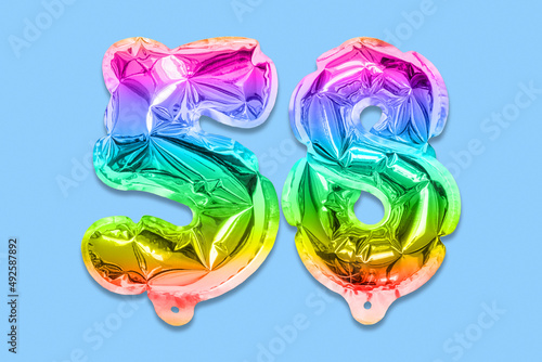 Rainbow foil balloon number, digit fifty eight on a blue background. Birthday greeting card with inscription 58. Top view. Numerical digit. Celebration event, template.