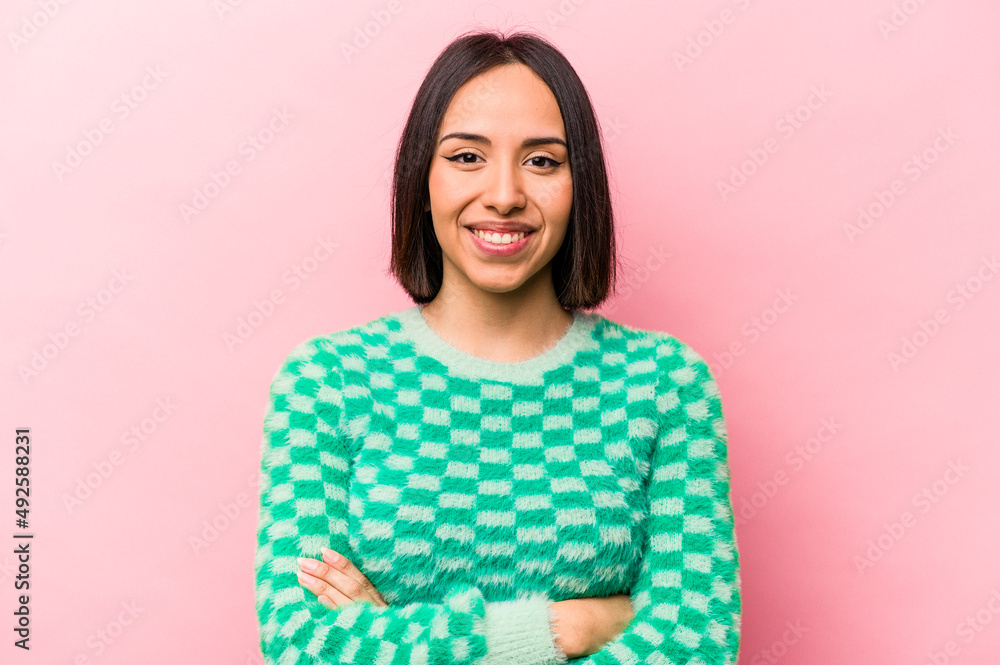 Young hispanic woman isolated on pink background who feels confident, crossing arms with determination. Young hispanic woman isolated on pink background who feels confident, crossing arms with determination.