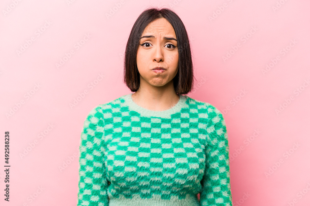Fototapeta premium Young hispanic woman isolated on pink background blows cheeks, has tired expression. Facial expression concept.