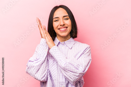 Young hispanic woman isolated on pink background feeling energetic and comfortable, rubbing hands confident. photo