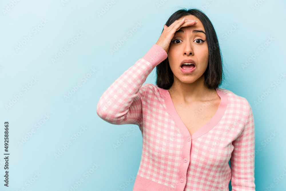 Young hispanic woman isolated on blue background shouts loud, keeps eyes opened and hands tense. Young hispanic woman isolated on blue background shouts loud, keeps eyes opened and hands tense.