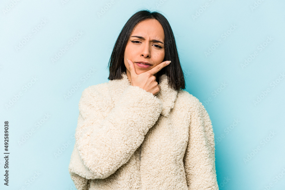 Young hispanic woman isolated on blue background contemplating, planning a strategy, thinking about the way of a business. Young hispanic woman isolated on blue background contemplating, planning a strategy, thinking about the way of a business.