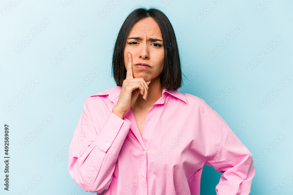 Young hispanic woman isolated on blue background unhappy looking in camera with sarcastic expression. Young hispanic woman isolated on blue background unhappy looking in camera with sarcastic expression.
