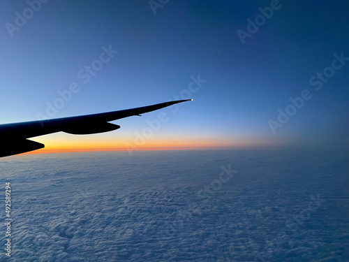 Airplane wing silhouette with an orange blue sky sunset © dina