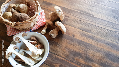 fresh noble forest mushrooms on a wooden table next to the basket. cooking mushrooms