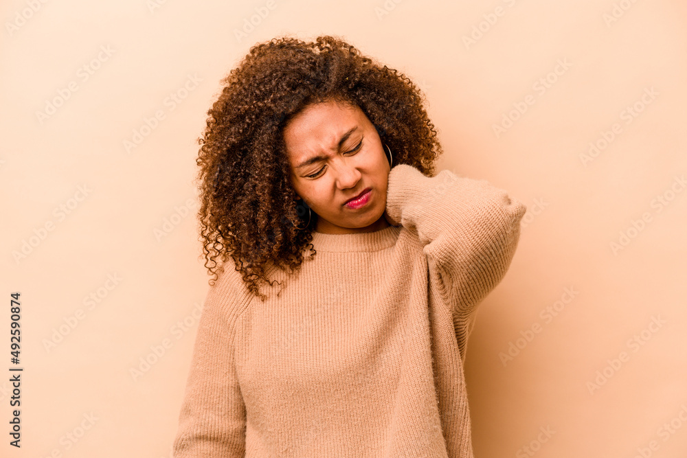 Young African American woman isolated on beige background suffering neck pain due to sedentary lifestyle. Young African American woman isolated on beige background suffering neck pain due to sedentary lifestyle.