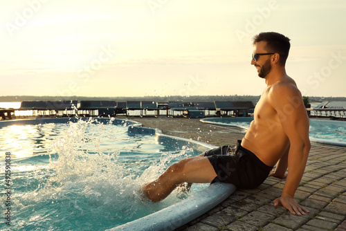 Happy man having fun near outdoor swimming pool on summer day