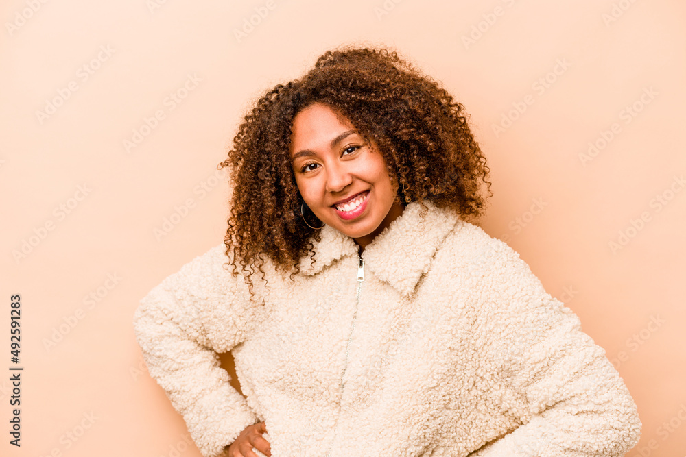 Young African American woman isolated on beige background happy, smiling and cheerful. Young African American woman isolated on beige background happy, smiling and cheerful.