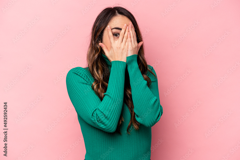 Young caucasian woman isolated on pink background blink through fingers frightened and nervous. Young caucasian woman isolated on pink background blink through fingers frightened and nervous.