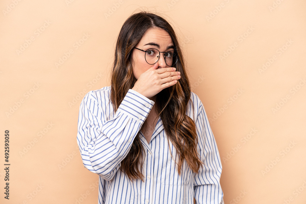 Young caucasian woman isolated on beige background covering mouth with hands looking worried. Young caucasian woman isolated on beige background covering mouth with hands looking worried.