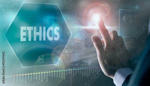A businessman controlling a futuristic display with a Ethics business concept on it.