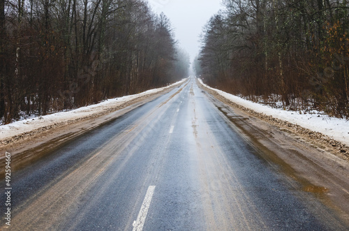 Asphalt road going into the distance during the thaw in winter. Dirty roadside from reagents © Ivan