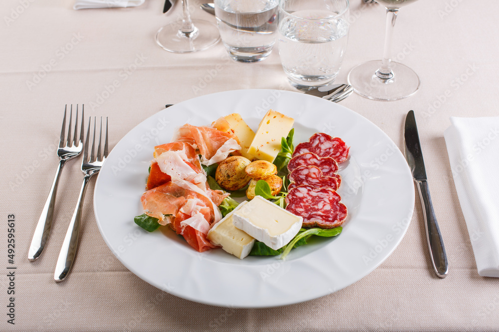 Antipasto di terra mediterraneo composto da salame, formaggi dolci e formaggi piccanti, scamorza, flan di verdure e prosciutto crudo servito in un ristorante elegante Antipasto di terra mediterraneo composto da salame, formaggi dolci e formaggi piccanti, scamorza, flan di verdure e prosciutto crudo servito in un ristorante elegante