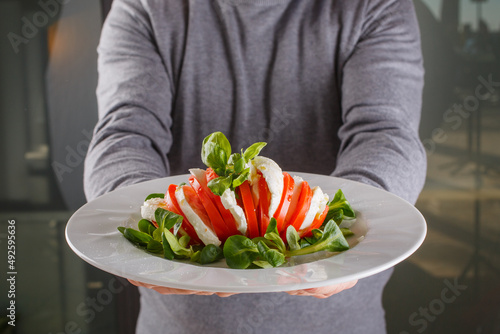 Caprese mediterranea composta a strati con mozzarella di bufala, pomodoro fresco e basilico fresco servita in un ristorante elegante photo