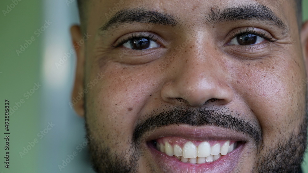 Fototapeta premium A smiling young black hispanic man close-up face looking at camera