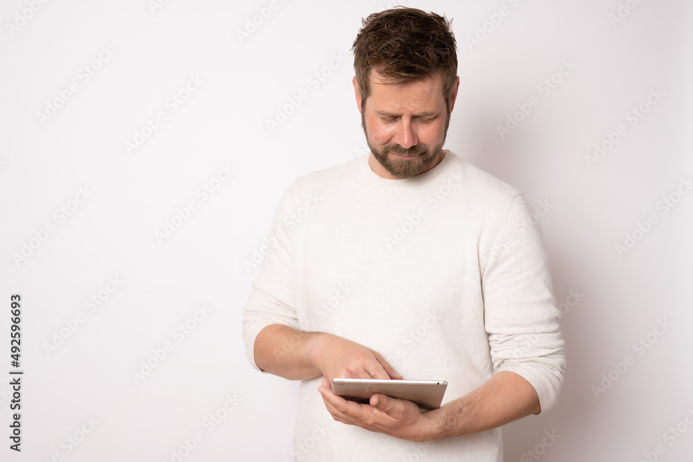 Young man in casual clothes using tablet standing isolated over white background. Business concept. Young man in casual clothes using tablet standing isolated over white background. Business concept.