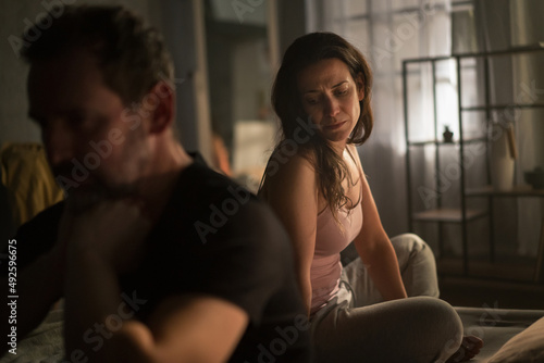 Foto Upset mature man with his wife in bed hehind him, relationship problems concept