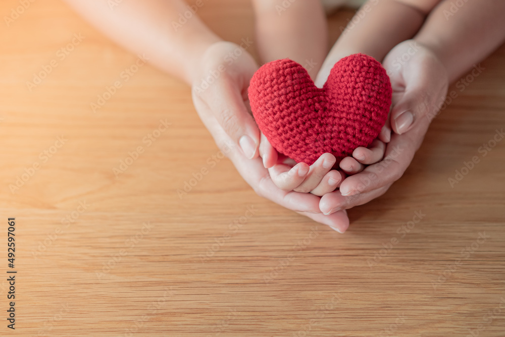 Adult and kid hands holding a yarn red heart. Hope, love, life concept Adult and kid hands holding a yarn red heart. Hope, love, life concept