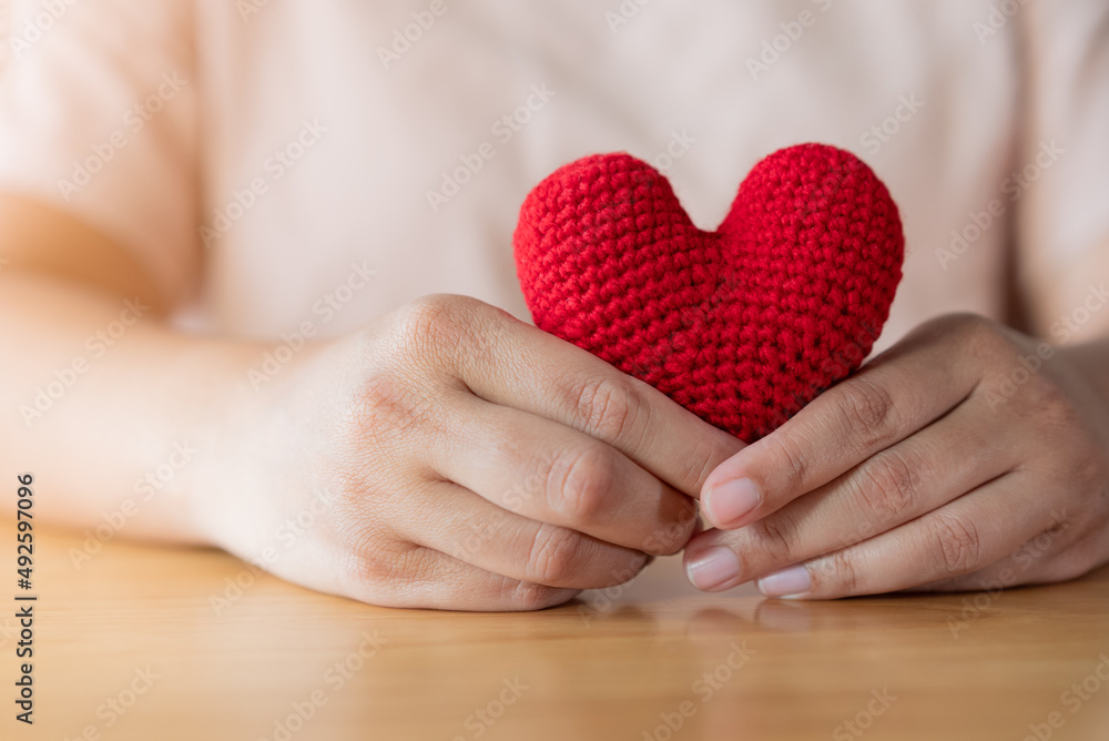 Adult hands holding a yarn red heart Adult hands holding a yarn red heart