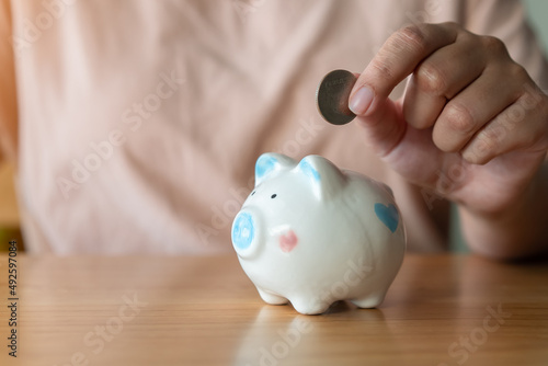 Adult hand saving putting coin into a piggy bank. Saving money for retirement, future concept