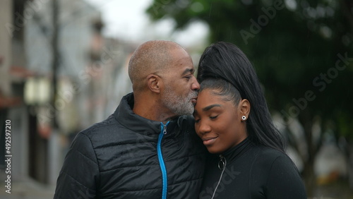 A black father kissing a teen daughter on forehead family love and affection