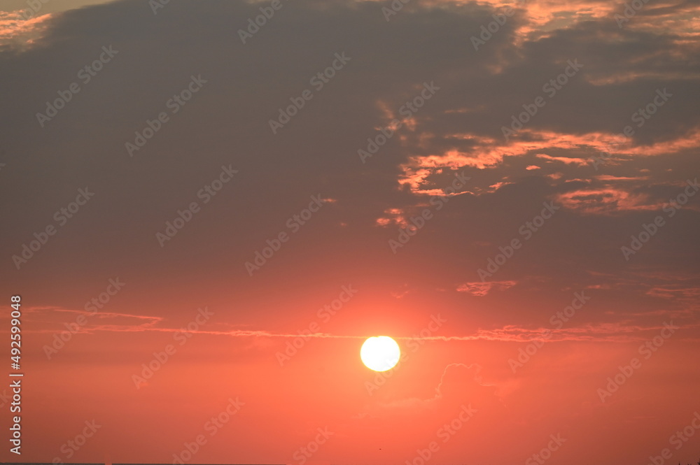 Sunset view on horizon with scattered clouds on a dusty day (PM 2.5). Bright orange sky at sunset.
