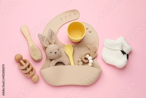 Flat lay composition with baby accessories and bib on pink background