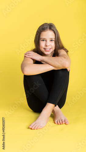 girl gymnast studio. little gymnast trains  shows a gymnastic element. do sport. Isolated on a colored yellow background. Young girl gymnast