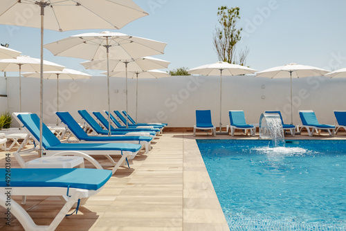 view of the pool with blue water, sun loungers and umbrellas