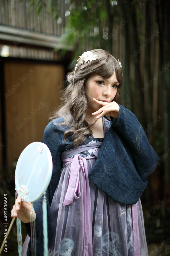 Beautiful young woman with dark blue Chinese lolita dress with Chinese garden Beautiful young woman with dark blue Chinese lolita dress with Chinese garden