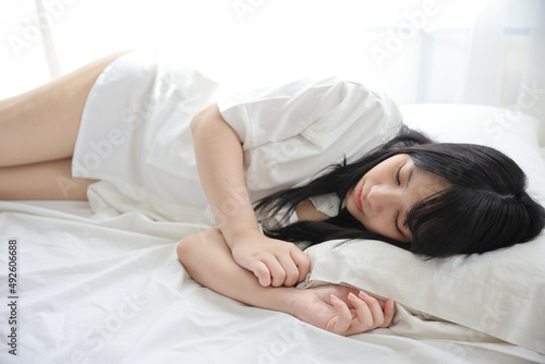Beautiful young woman waking up in the morning at white bedroom