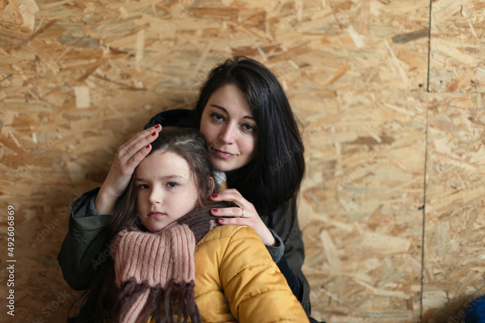 Ukrainian war refugees in temporary shelter and help center, little girl with her mother.