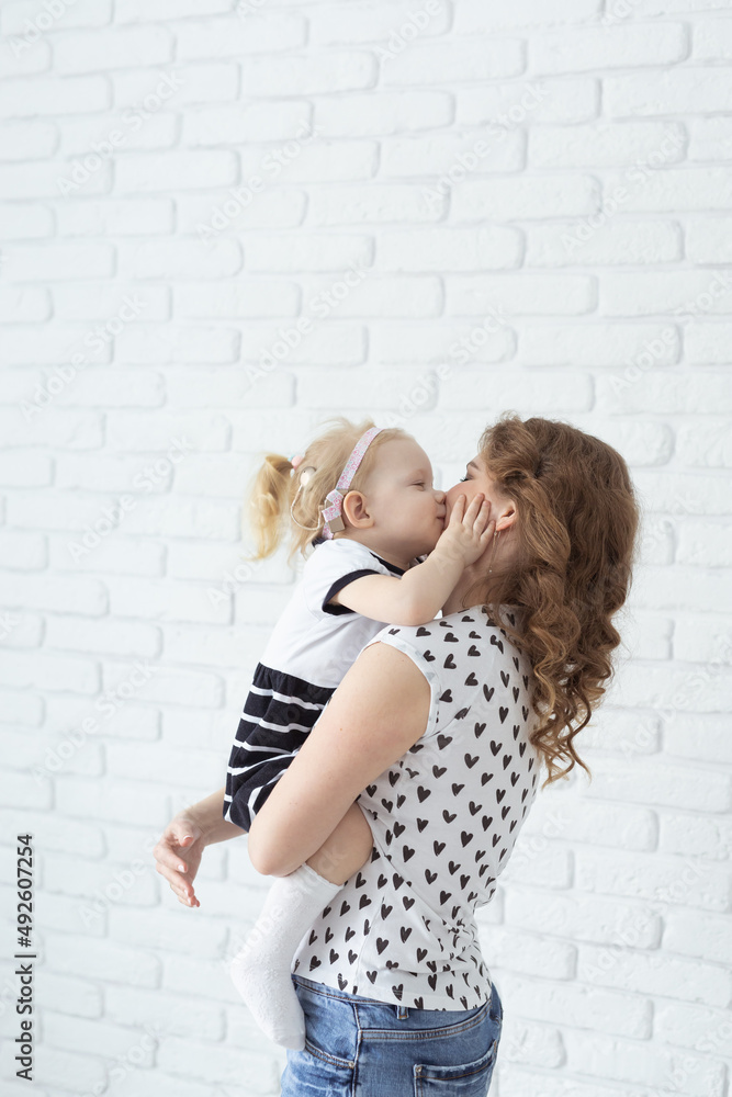 Mother holds her child with hearing aids and cochlear implants on white brick wall . Deaf and health concept Mother holds her child with hearing aids and cochlear implants on white brick wall . Deaf and health concept