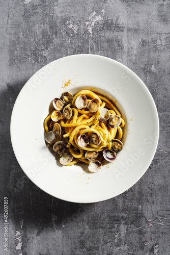 fresh homemade spaghetti pasta with clams and bottarga caviar on a concrete surface photo