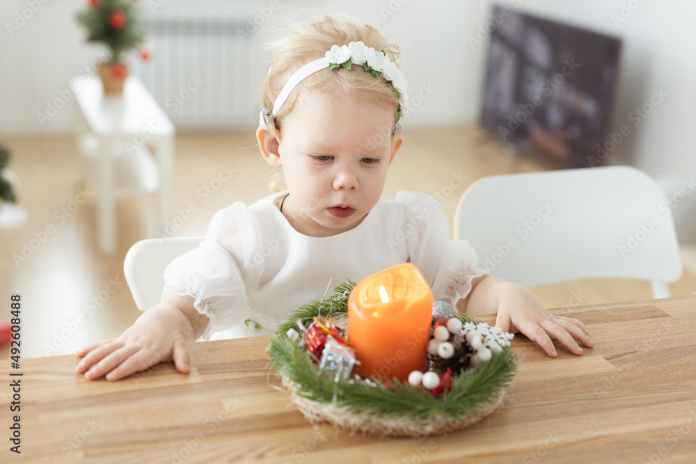 Baby child with hearing aids and cochlear implants plays with candle. Deaf and health concept Baby child with hearing aids and cochlear implants plays with candle. Deaf and health concept