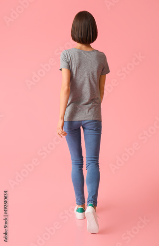 Beautiful young woman in stylish t-shirt on color background, back view