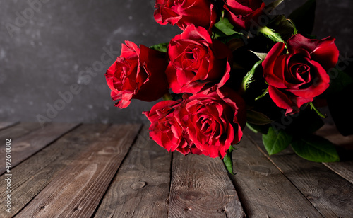 Fototapeta Naklejka Na Ścianę i Meble -  Bouquet of red roses for mother's day on old wood. Atmospheric vintage background for mother's day greetings with short depth of field and space for text. Close-up