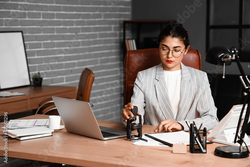 Female notary public attaching seal to document in office photo