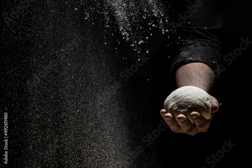 White flour flying into air as pastry chef in white suit slams ball dough on white powder covered table. concept of nature, Italy, food, diet and bio