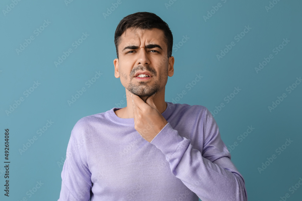Ill young man with sore throat on blue background Ill young man with sore throat on blue background