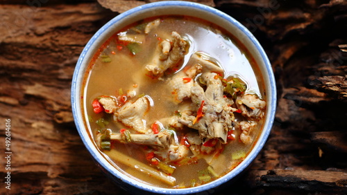 Chicken Feet Spicy Soup (Tom Yum Gai) Thai native spicy food in white bowl on wooden background, Thai Food
