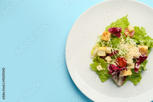 Plate with tasty vegan Caesar salad on blue background