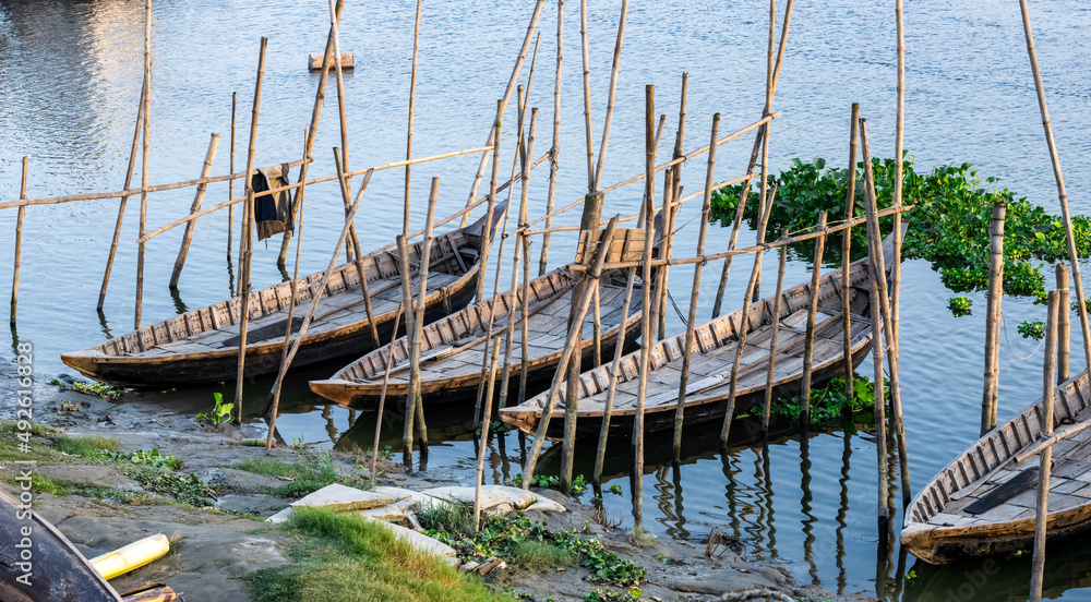 Fototapeta premium A row of parked wooden passenger boats on the river in the rural village