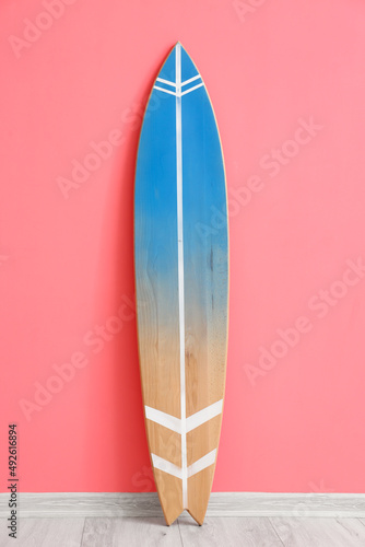 Wooden surfboard near pink wall