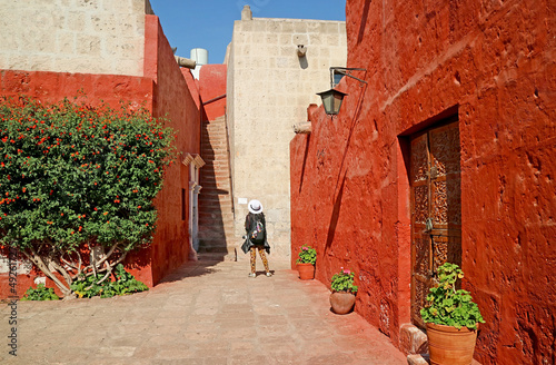 Visitor being impressed by vivid red ans white colored historic buildings in the convent of Santa Catalina de Siena, Arequipa, Peru photo