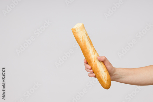 bitten baguette bread in a female hand on a white background close-up